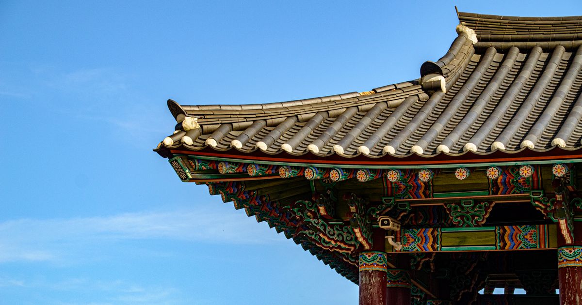 파란 하늘 아래 단청을 칠한 전통 건물의 처마와 기와지붕